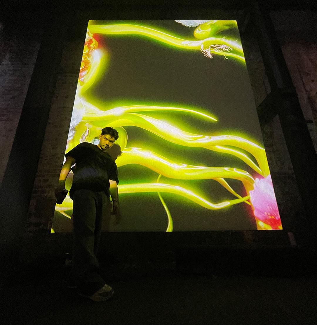 jonathan standing in front of a large screen projecting a bright green animation 